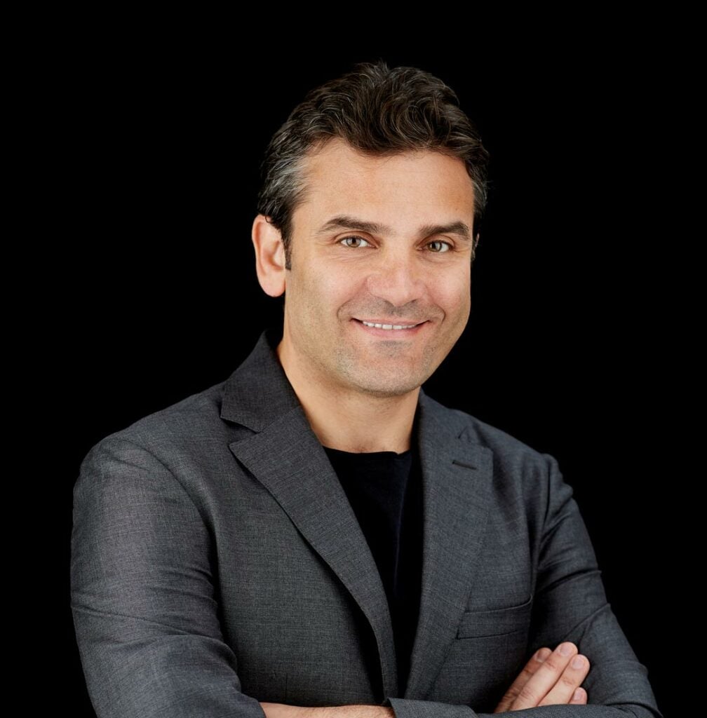 Dr. Ahmad Saad in gray suit on black background.