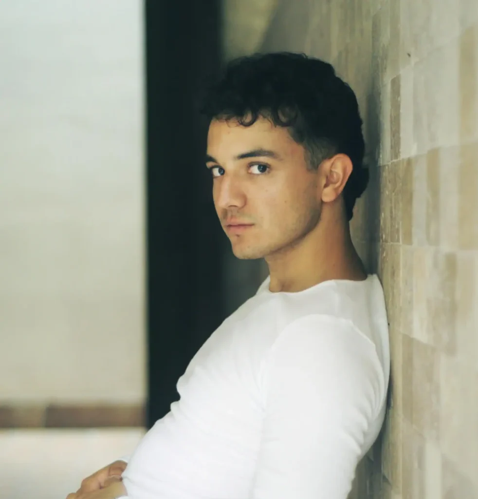 Man leaning on the wall and flexing the results of his neck and chin liposuction recovery