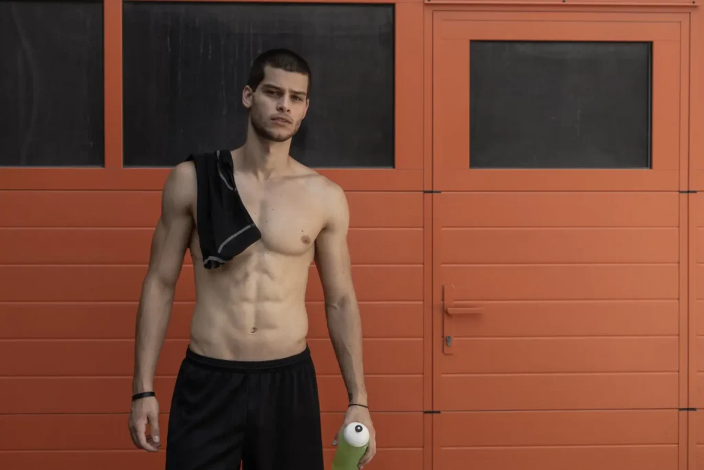 Shirtless man flexing the results of his tummy tuck procedure