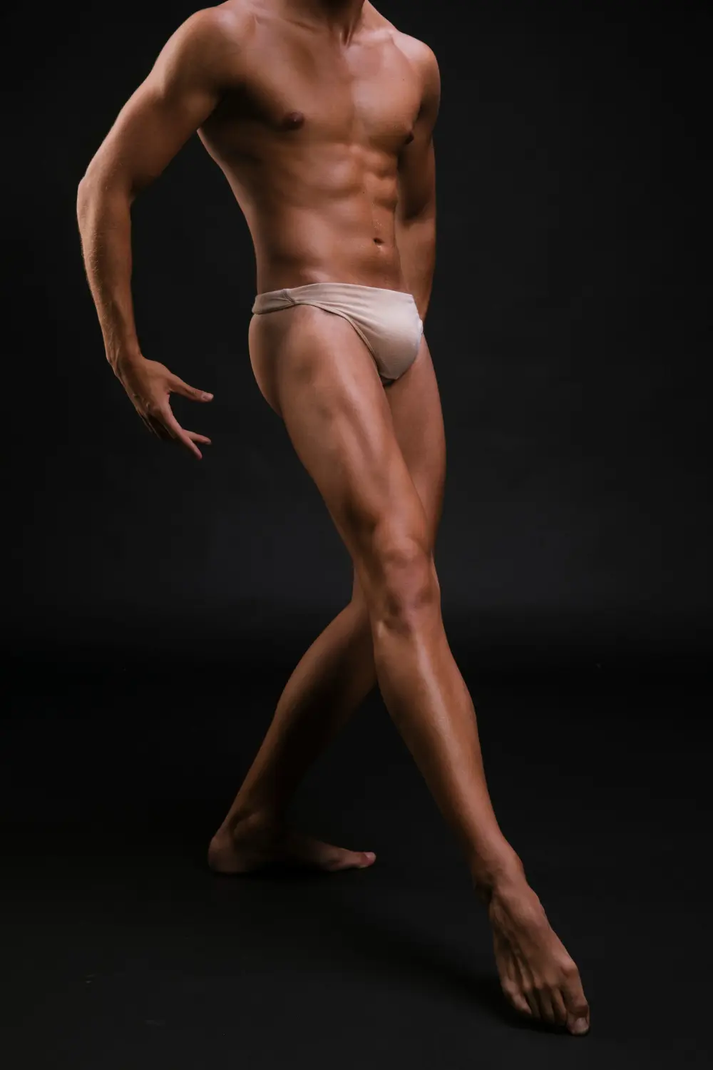A lean, muscular physique showcasing sculpted abs and toned, lifted lower body legs in a graceful dynamic pose