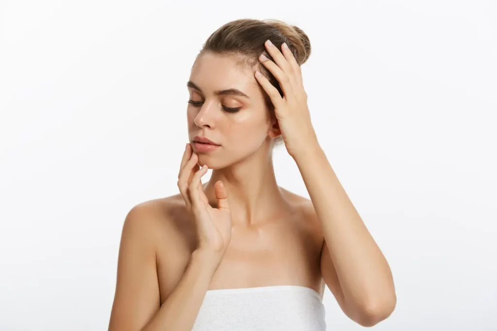 A woman with glowing, youthful skin gently touching her face and jawline