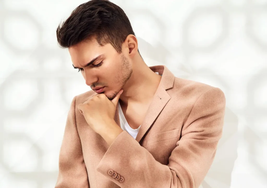 Fashion stylish model dressed in elegant light pink suit posing near white wall