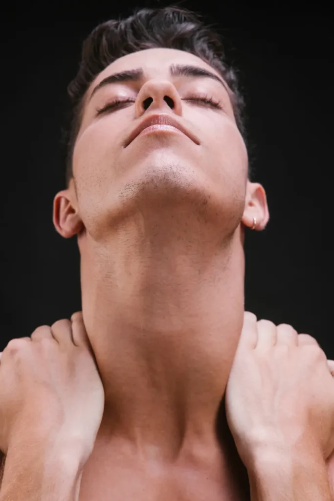 Person tilting head back to showcase neck contour and jawline for neck plastic surgery consultation