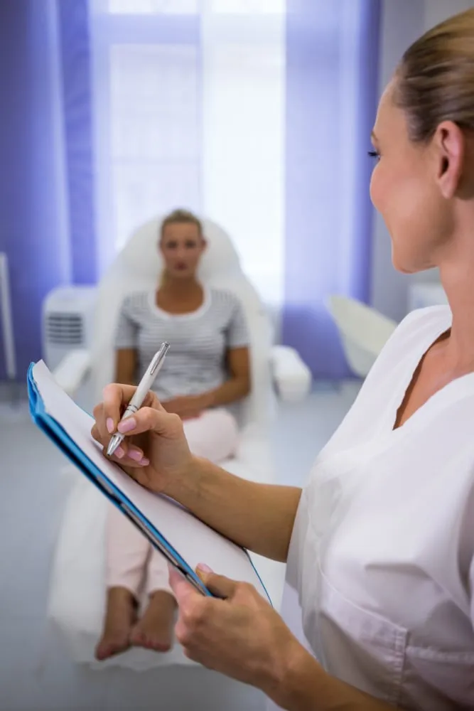 Plastic surgeon writing medical reports while talking to patient
