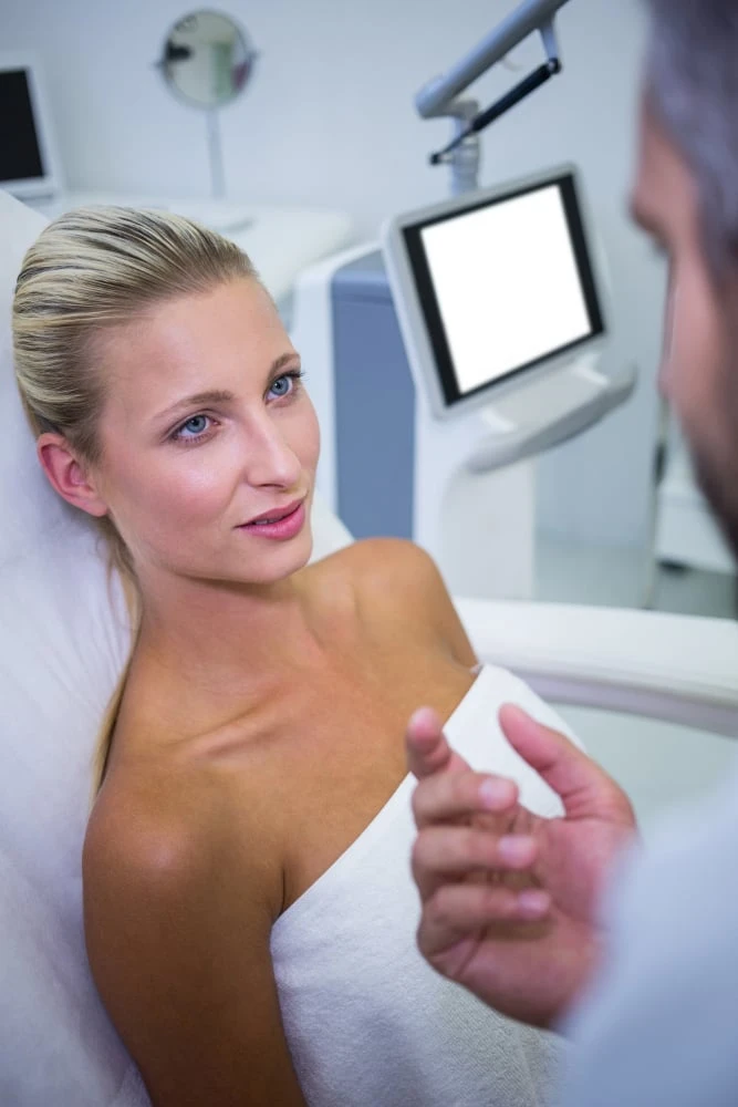 Female patient lying and looking at Plastic Surgeon