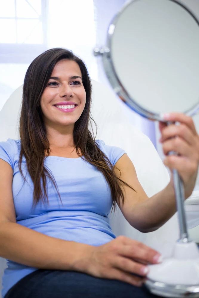Smiling patient looking in the mirror before plastic surgery
