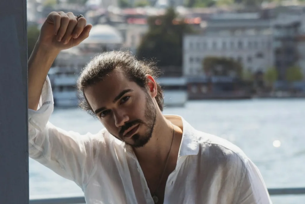 Man wearing loose white buttoned shirt while flexing his defined facial profile after getting neck and jawline contouring