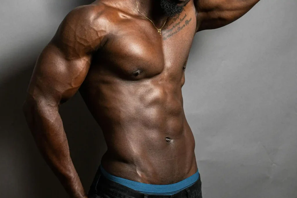 Medium shot of a dark skinned man with sculpted abs after tummy tuck