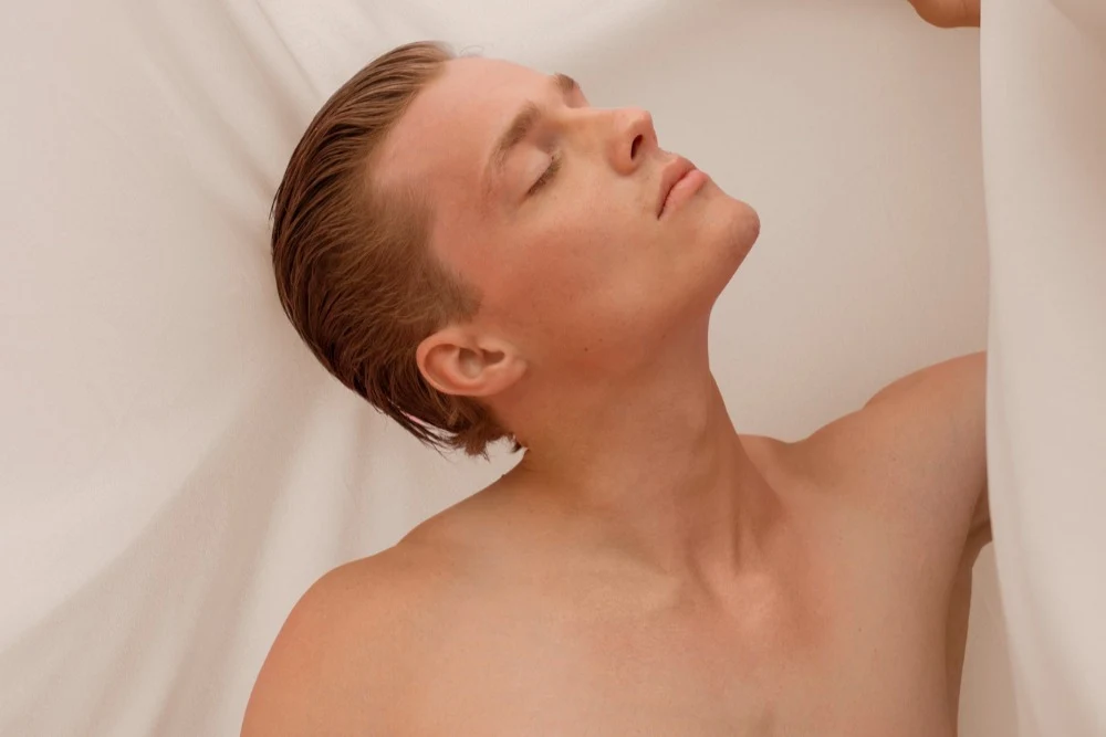 Shirtless man flexing his defined neck contour after getting neck liposuction