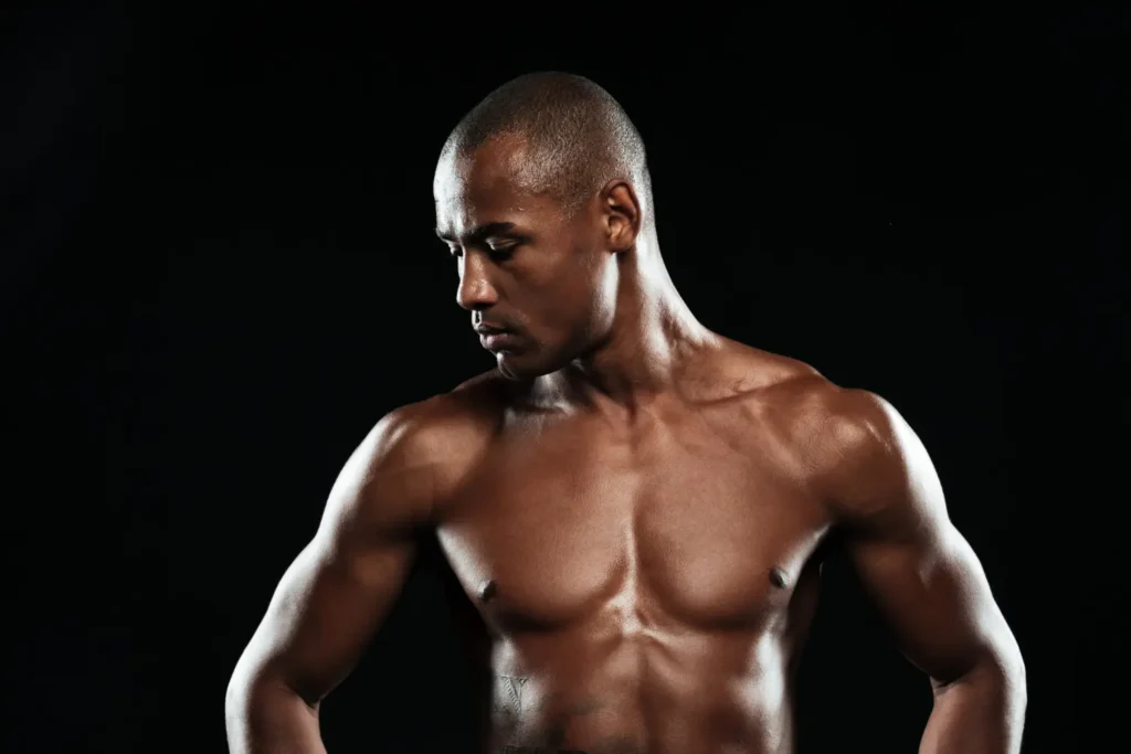 Shirtless man in a black background showing his sculpted abs after getting liposuction