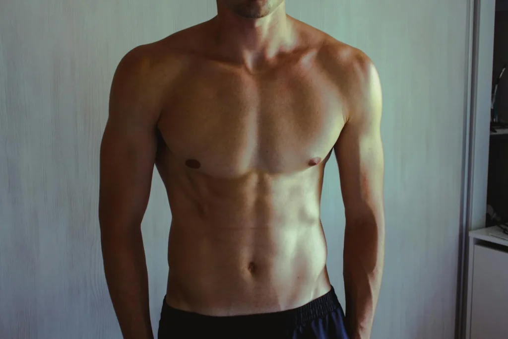 Shirtless man with hands in his pockets looking sculpted and more manly after getting a love handle liposuction