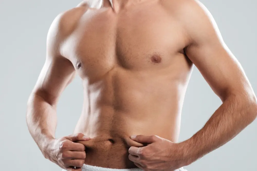 A man pinches fat on his midsection, often a key moment for those considering how liposuction can address specific body contouring