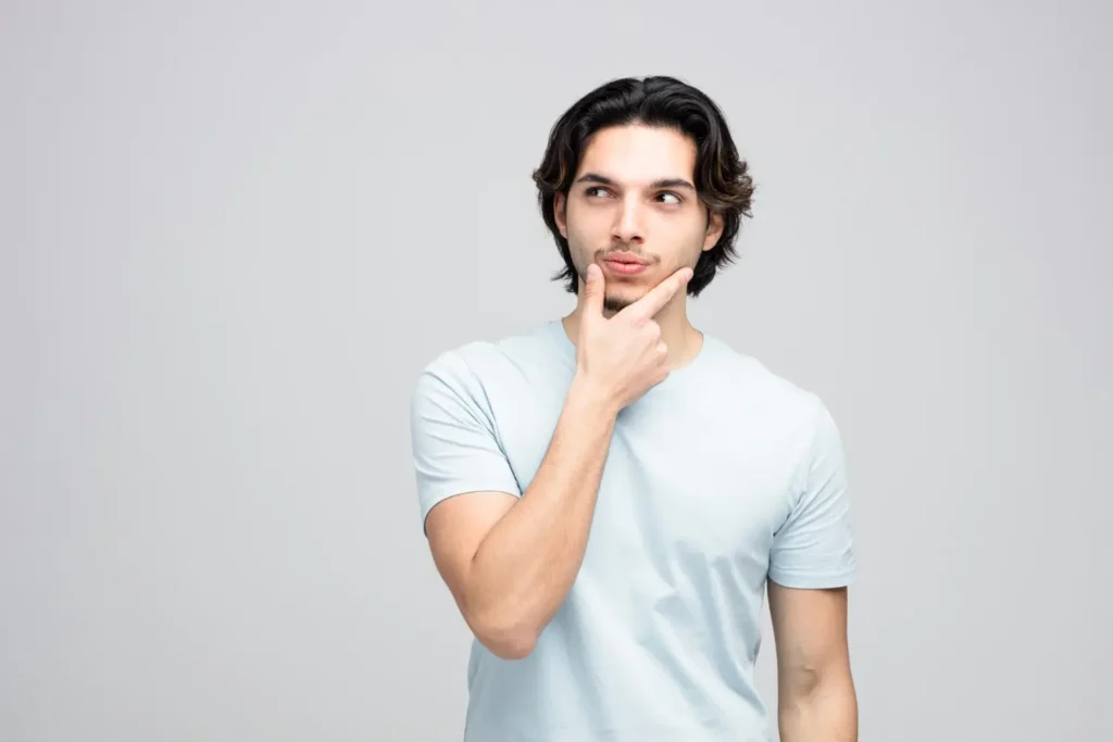 A thoughtful young man touches his chin as if considering options