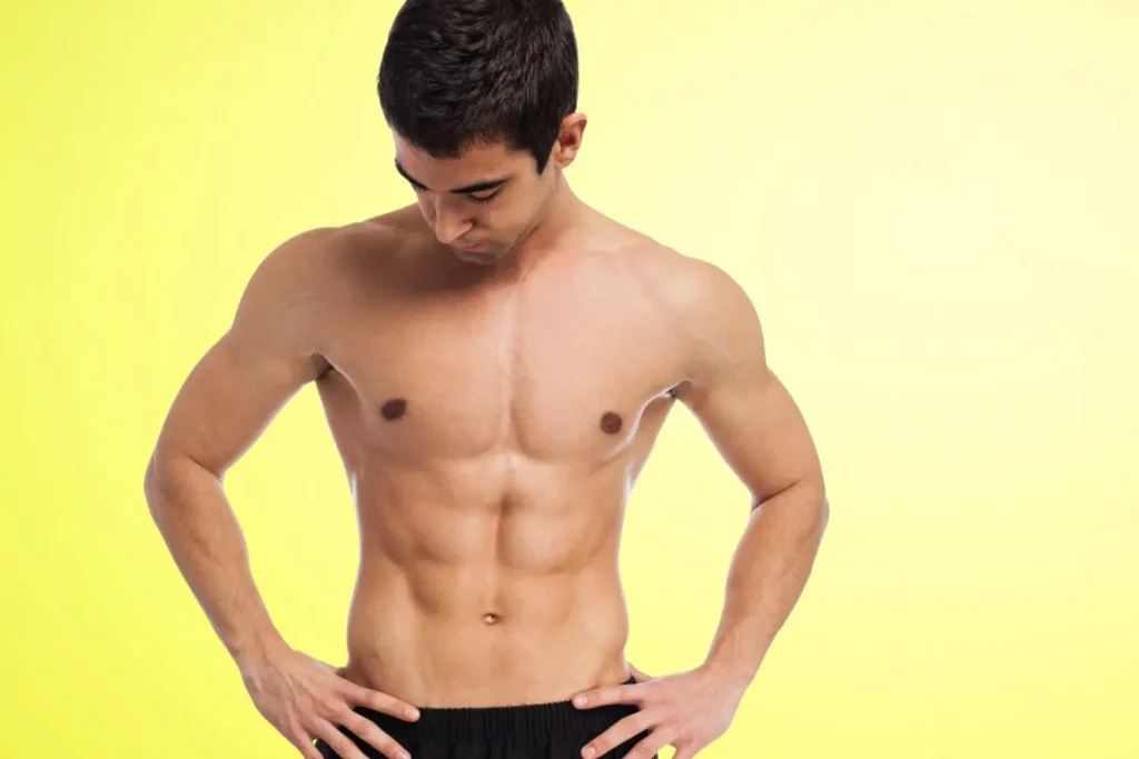 Fit man looking down at his toned, flat abdomen showing the type of smooth abdominal results achievable with a tummy tuck procedure