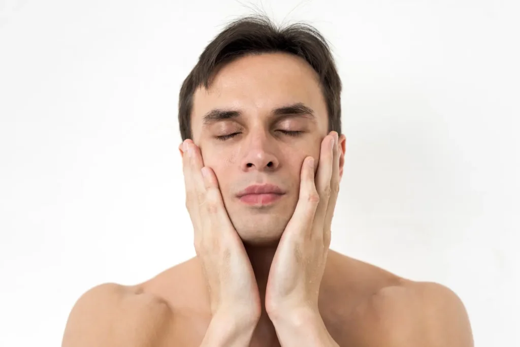 Man gently holding his face to assess skin laxity and elasticity, key factors that influence how many FaceTite sessions are needed