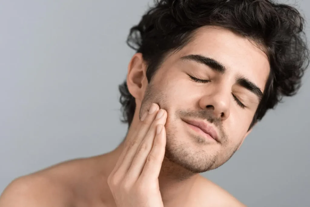 Young man feeling his jawline to determine FaceTite candidacy