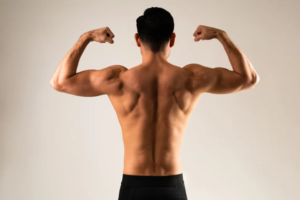 Rear view of a young man flexing his muscles and showing his muscular back