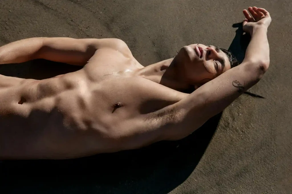 Man lying on the sand showing his tummy tuck results