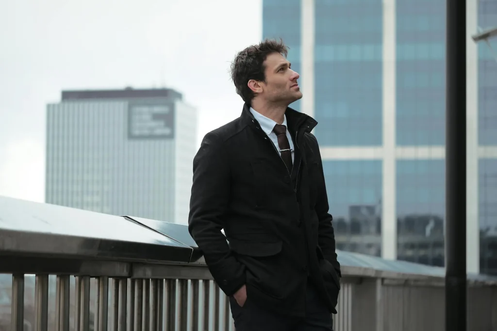 Man outside wearing black coat and showing off his FaceTite results