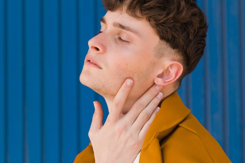 Man touching his face after getting a neck and jawline contouring