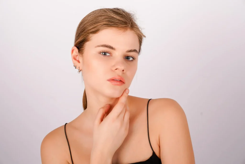 Woman touching her sculpted jawline after receiving dermal fillers