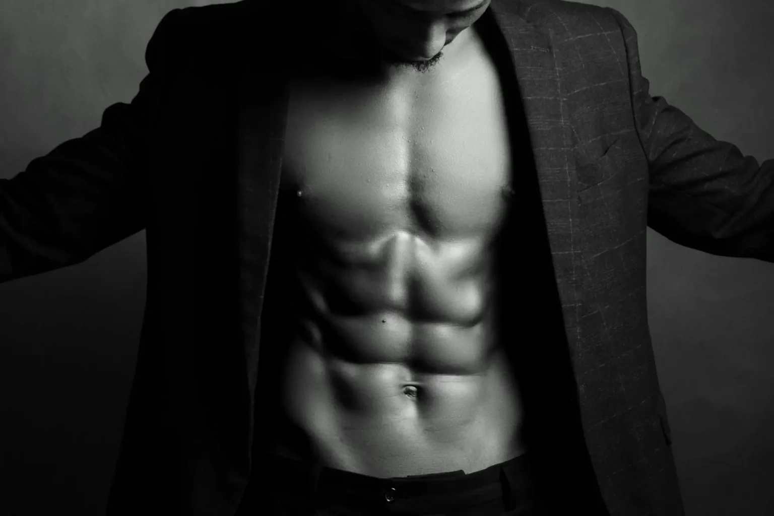 Man wearing a coat and showing off his toned abdomen after liposuction recovery