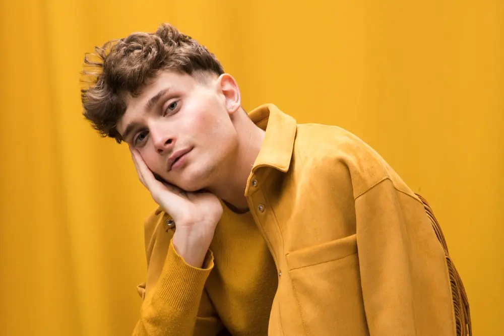 Man wearing yellow jacket and holding face after getting PDO threads