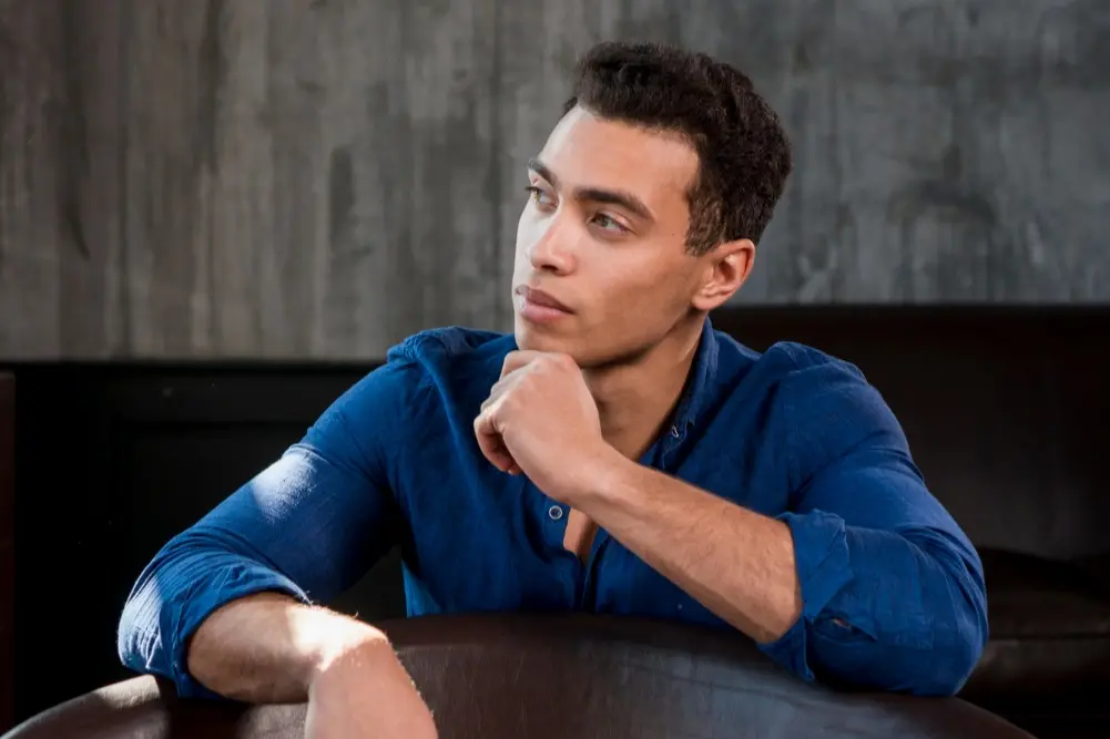 A man sits in deep thought with his hand on his chin, illustrating the common question of whether Botox is considered a plastic surgery