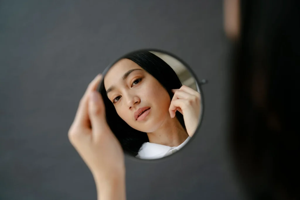 Woman checking her face on the mirror before getting neck liposuction