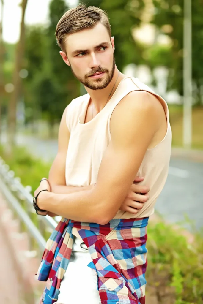 Hipster handsome man guy in stylish summer clothes posing in the street
