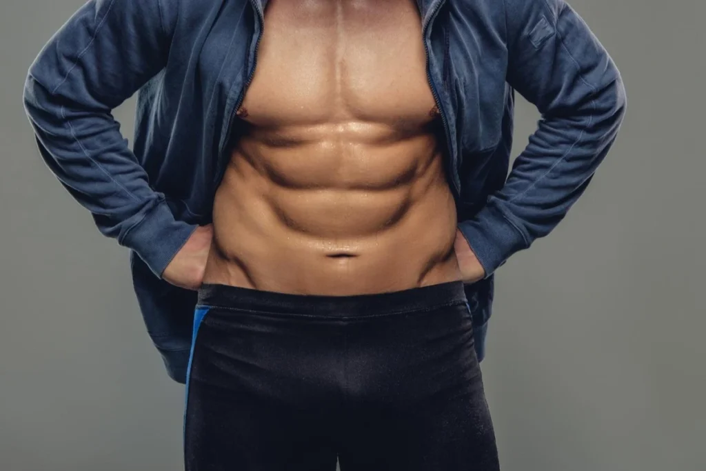 Abdominal man in a blue hoodie isolated on a grey background.