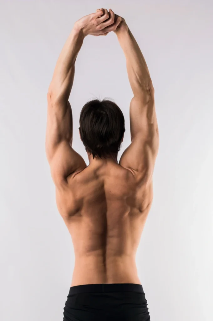 Back view of shirtless muscled man with arms up