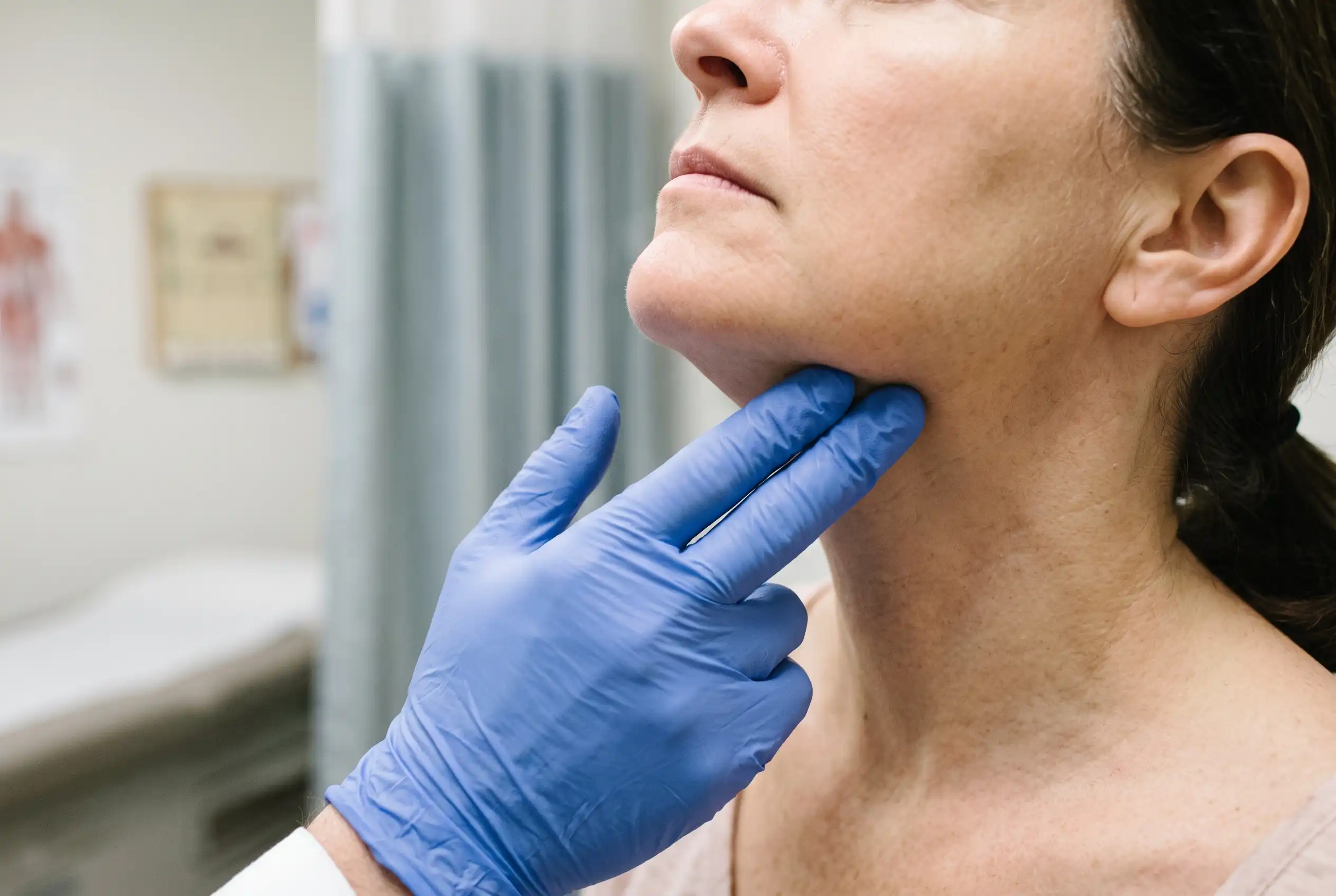 Clinician checking whether neck lipo swelling is fluid or early scar tissue
