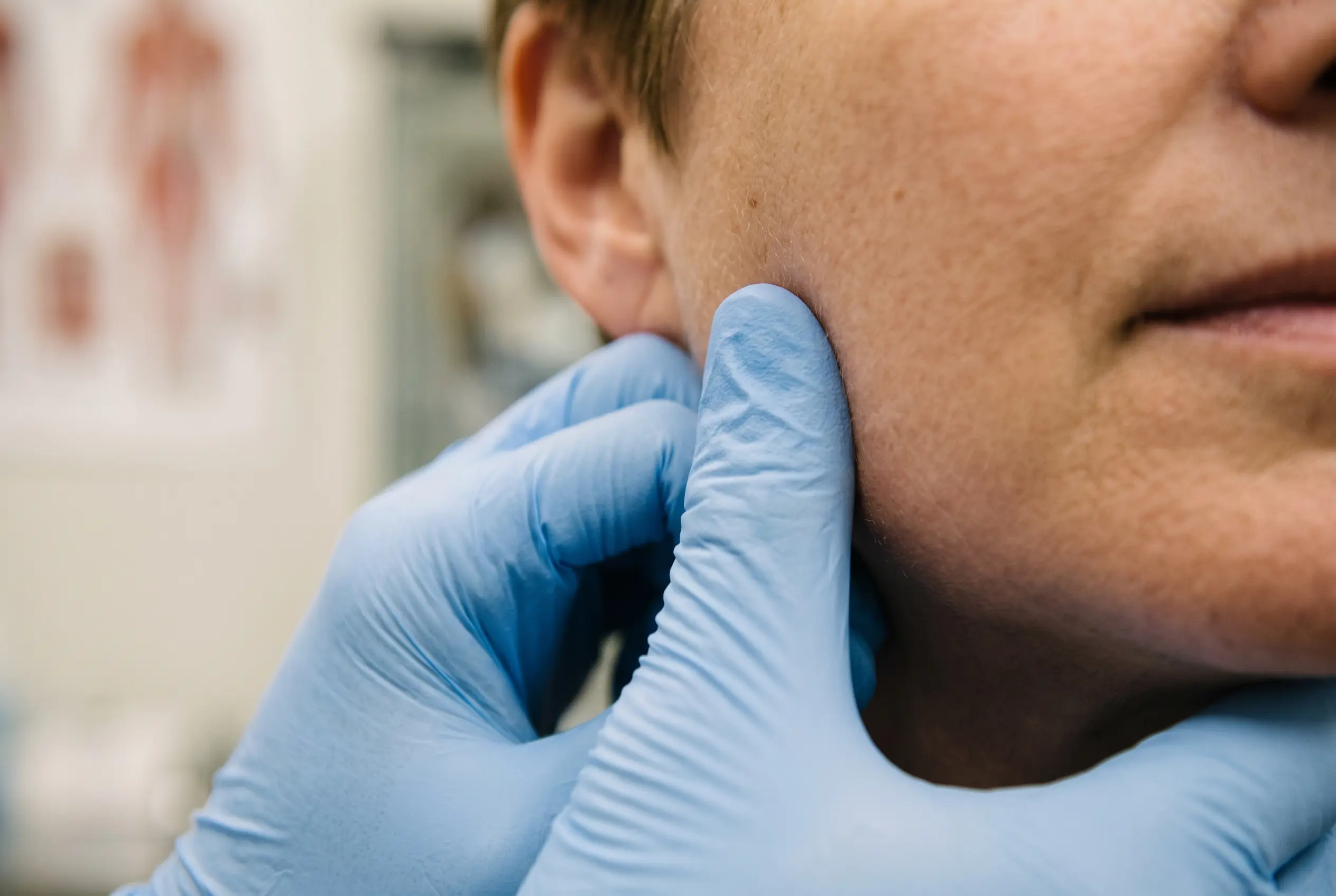 Clinician palpating the masseter to check whether jaw pain is muscular