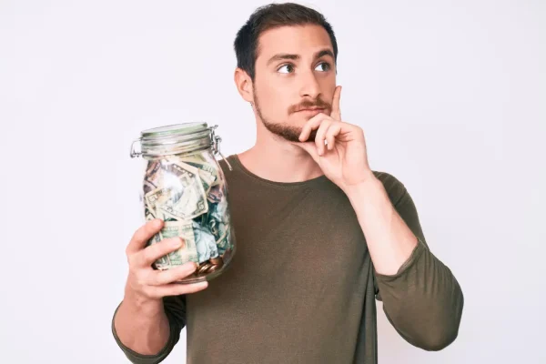 Man holding a jar with cash and thinking of getting a plastic surgery
