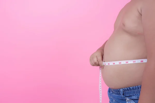 Man measuring belly before undergoing Sermorelin peptide therapy