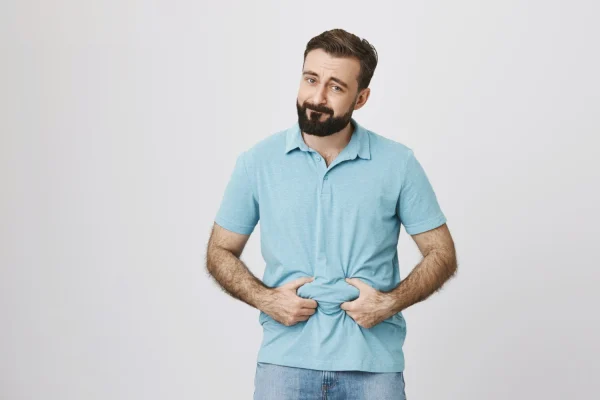 Man pinching his belly fat and thinking about getting liposuction