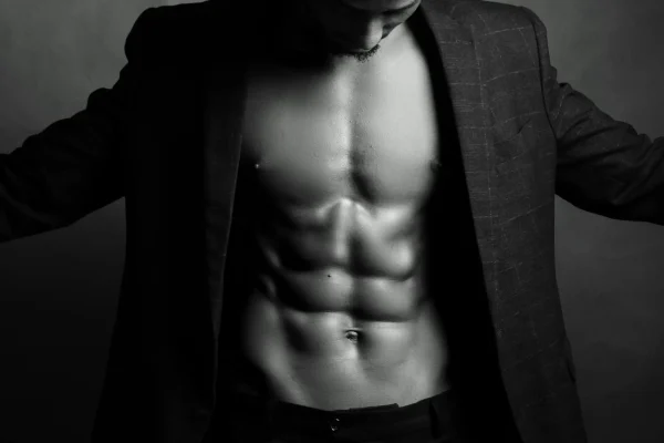 Man wearing a coat and showing off his toned abdomen after liposuction recovery
