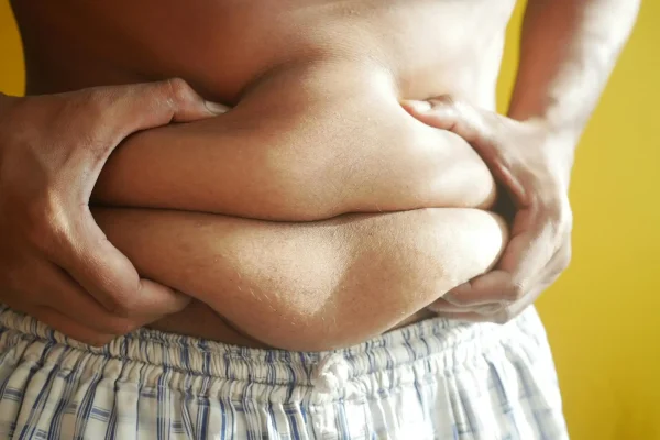 Person pinching their stomach and is planning to get a tummy tuck