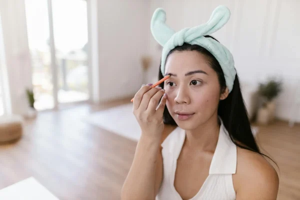 Woman applying makeup and seeing the slight brow lift that her Botox injection has given