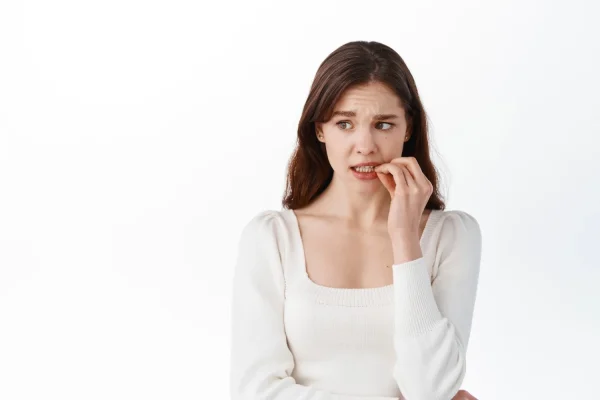 Woman wearing a white blouse and looking scared upon knowing about jawline fillers gone wrong