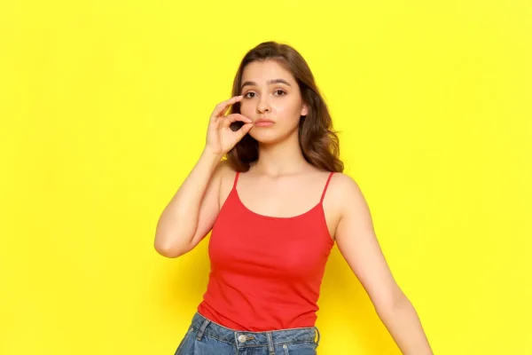Woman wearing red top with yellow background thinking if PDO threads are worth it