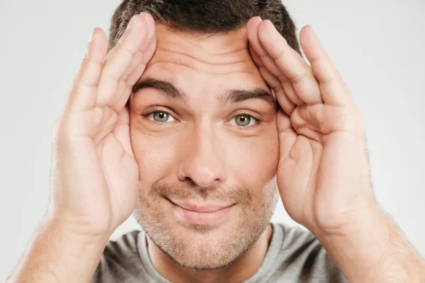 Man covering his frown lines and thinking of getting Botox injections