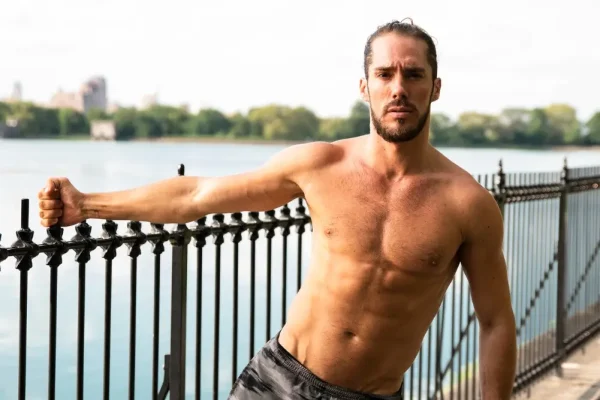 Man flexing the results of his HD liposuction procedure after recovery