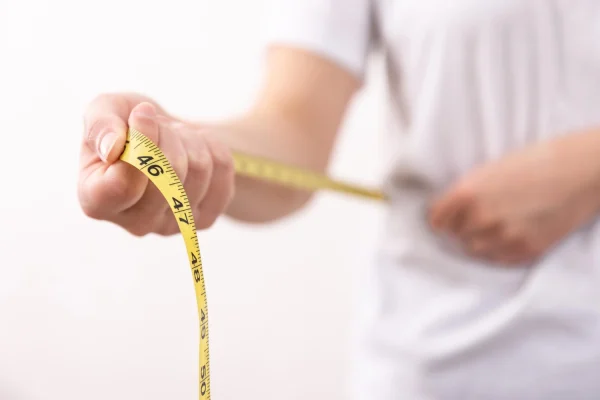 Man measuring his abdomen before getting liposuction