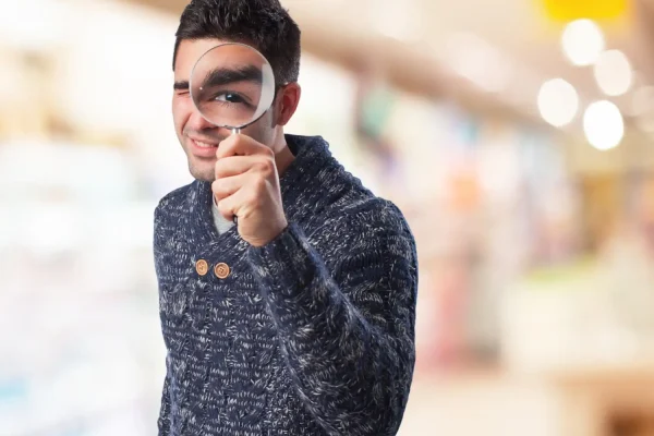 Man wearing a sweater and holding a magnifying glass indicating sourcing high quality PRP