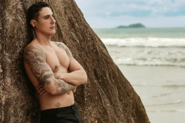 Topless man leaning on a tree while showing his tummy tuck results