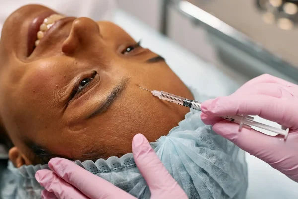 Woman smiling while being injected with Botox on the forehead