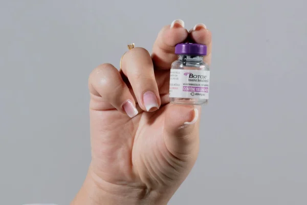 Close-up shot of a hand holding a vial containing Botox