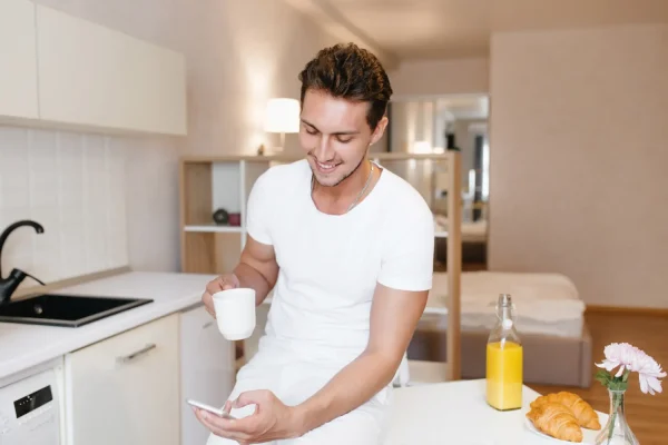 Man holding a mug and phone preparing for his tummy tuck procedure